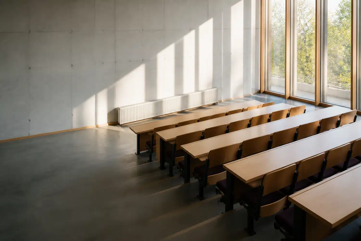 Illustrative empty daylit study hall with rows of desks and tall windows