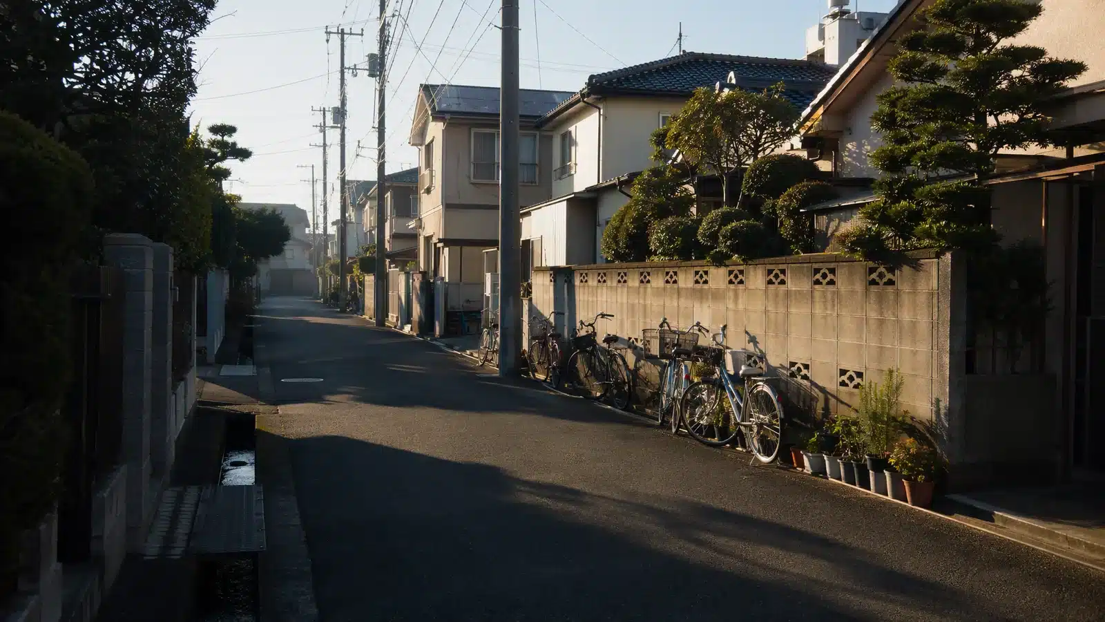 Illustrative residential lane in Japan with utility poles, parked bicycles and low tiled houses