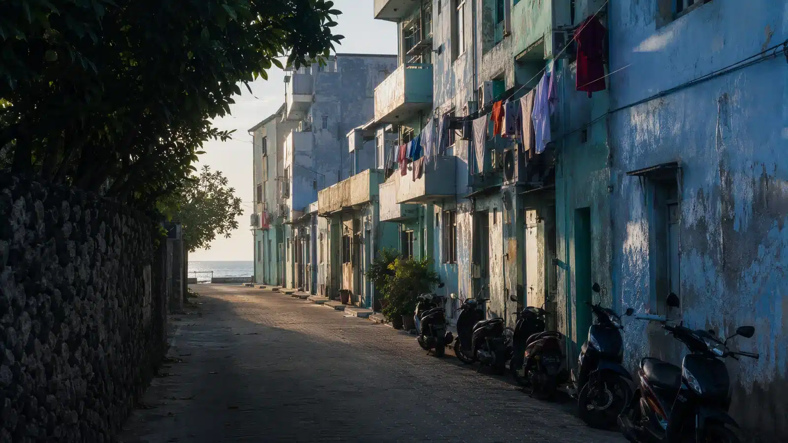 Illustrative residential street in the Maldives with painted low-rise buildings and parked scooters