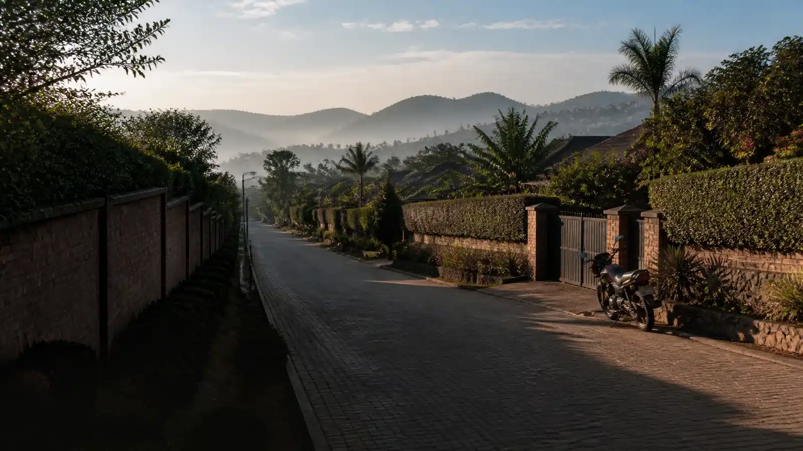 Illustrative hillside residential street in Rwanda with brick walls, hedges and mist over the valleys