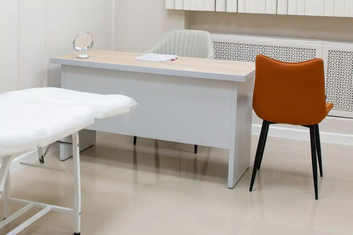 A consultation desk and chair in an unoccupied clinic room.