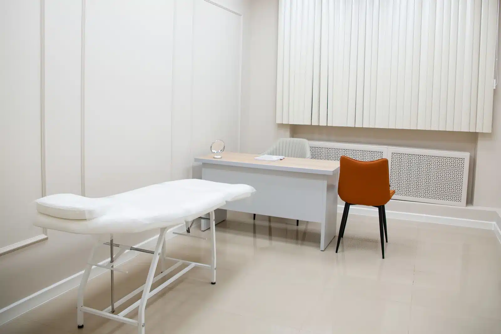 An unoccupied treatment room with white walls, a couch and a desk. Illustrative photograph, not a named partner hospital.
