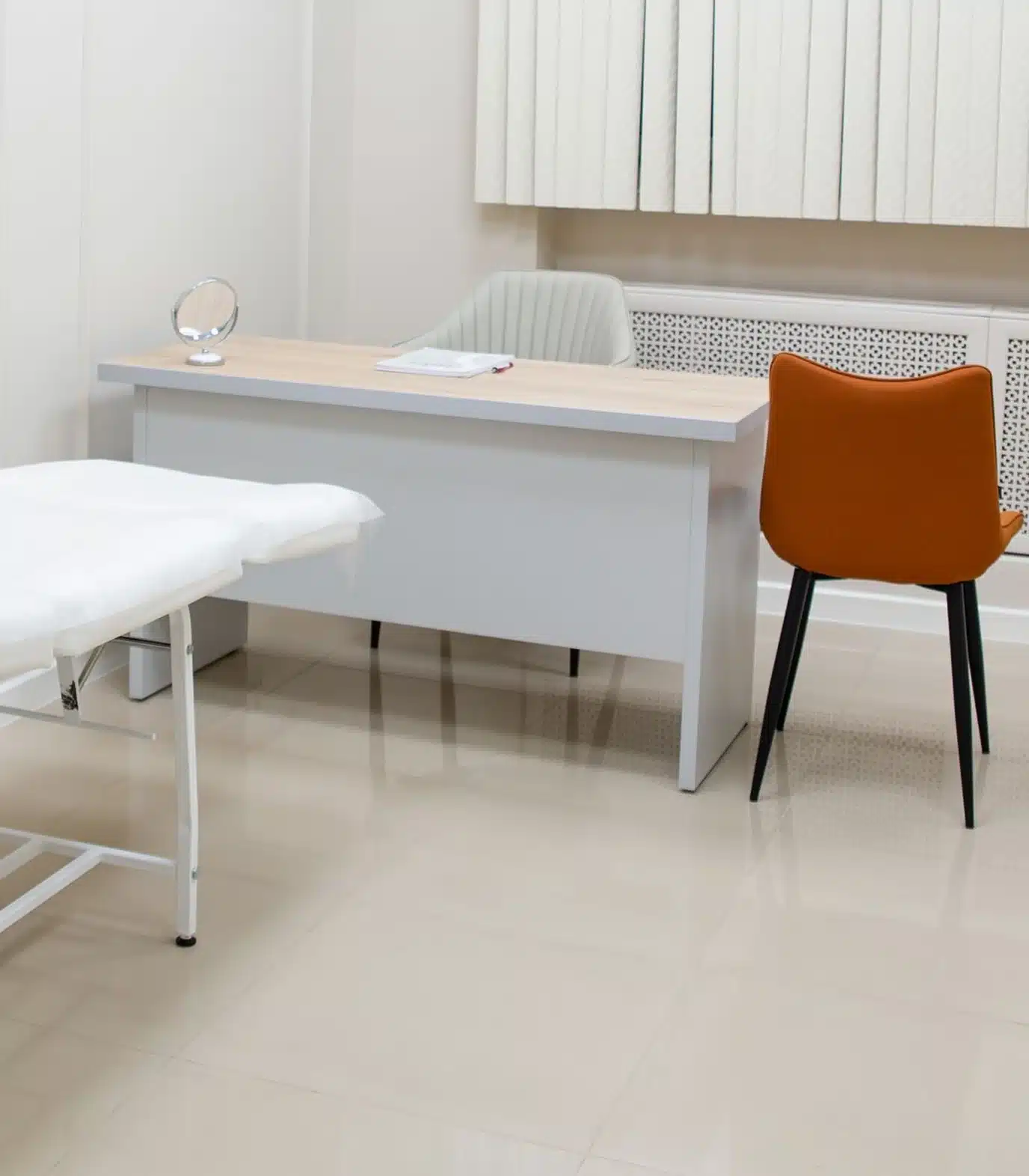 An unoccupied treatment room with a treatment couch, a desk and a chair. Illustrative photograph, not a named partner hospital.